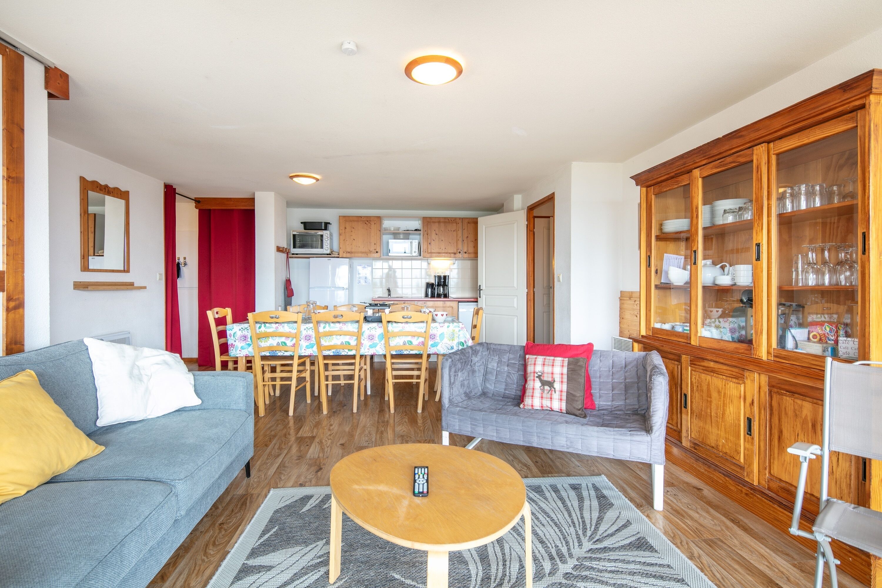 A living room with a sofa, a coffee table, and a dining area with chairs and a table.