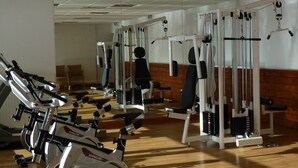 Un gimnasio con diversos equipos de ejercicio, incluyendo cintas de correr, máquinas de pesas y pesas sueltas.