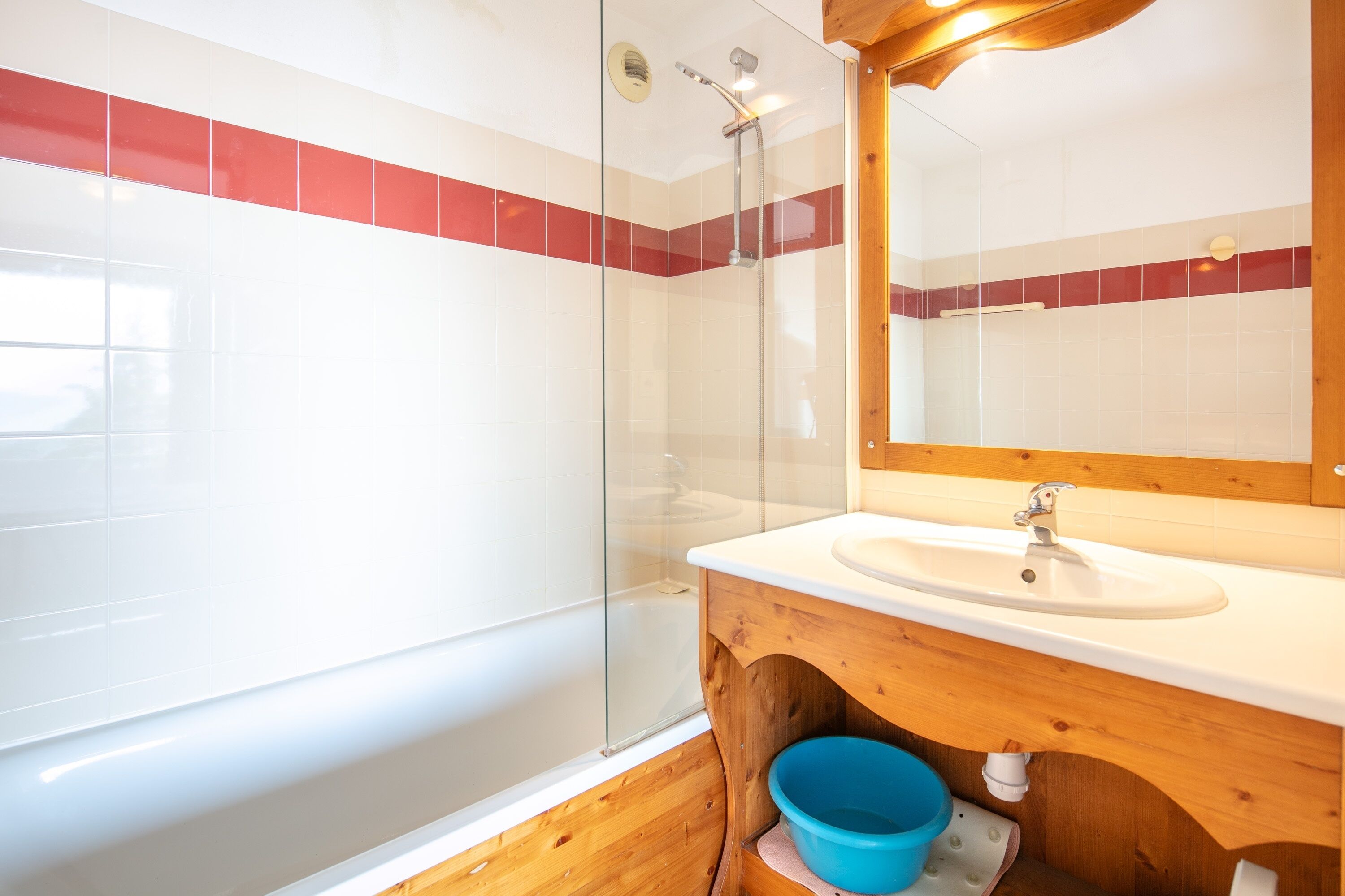 A bathroom with a glass shower enclosure, a wooden vanity with a sink, and a mirror above the vanity.