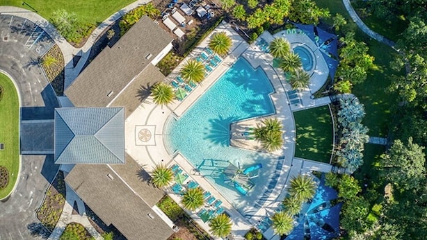 Vue aérienne d’un complexe hôtelier doté d’une piscine centrale, d’espaces de détente et de palmiers.