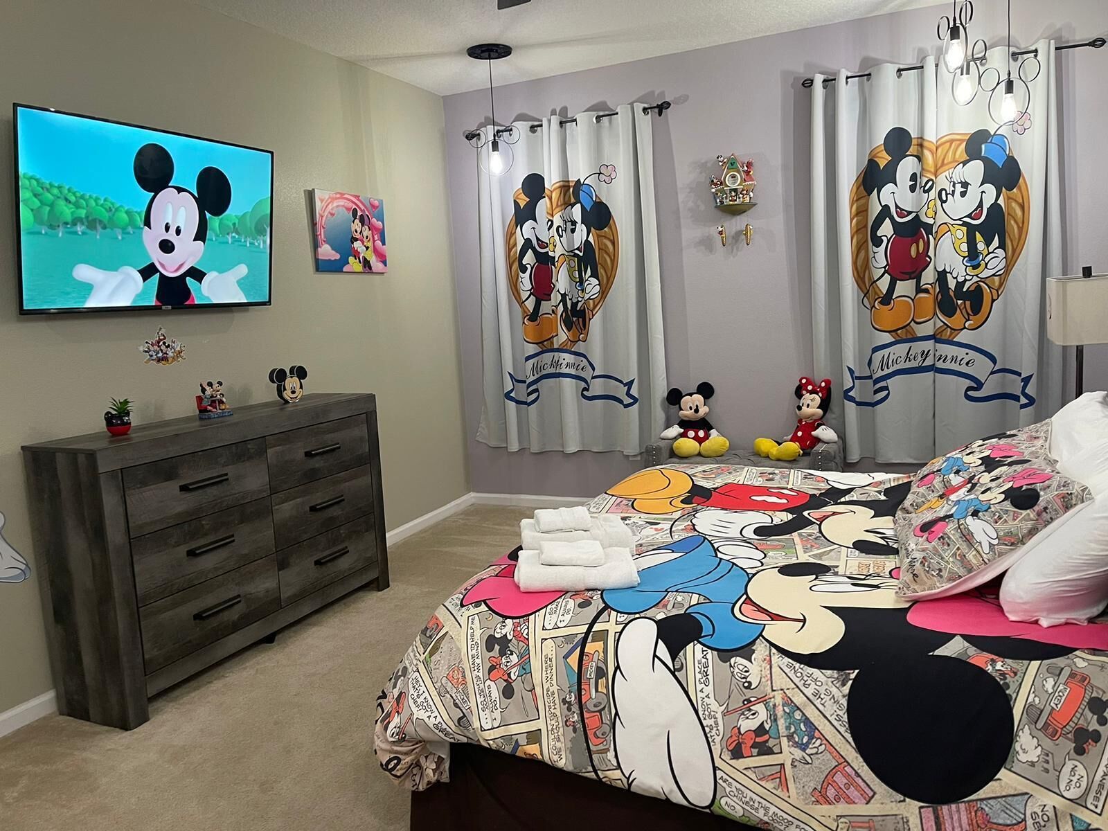 A bedroom with Mickey and Minnie Mouse themed decor, including curtains, bedding, and wall art.