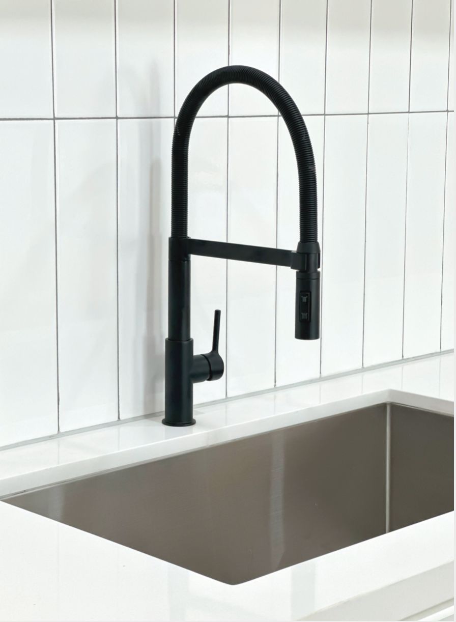 Cozinha moderna com torneira preta, azulejos brancos e uma pia retangular.