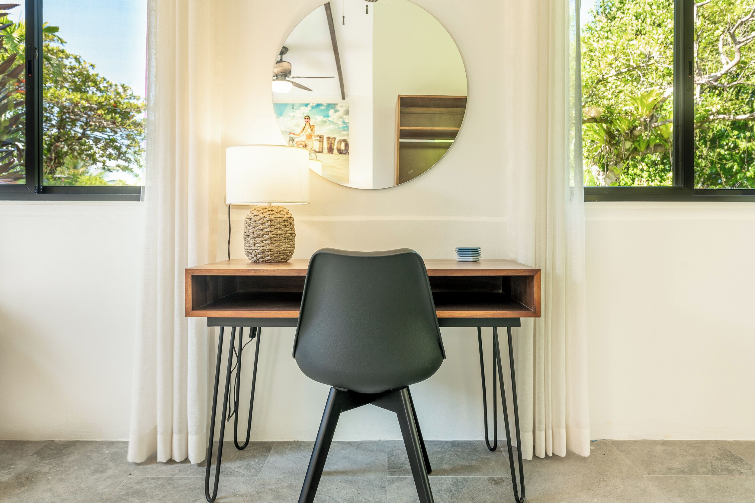A modern room with a desk, chair, and a round mirror on the wall.