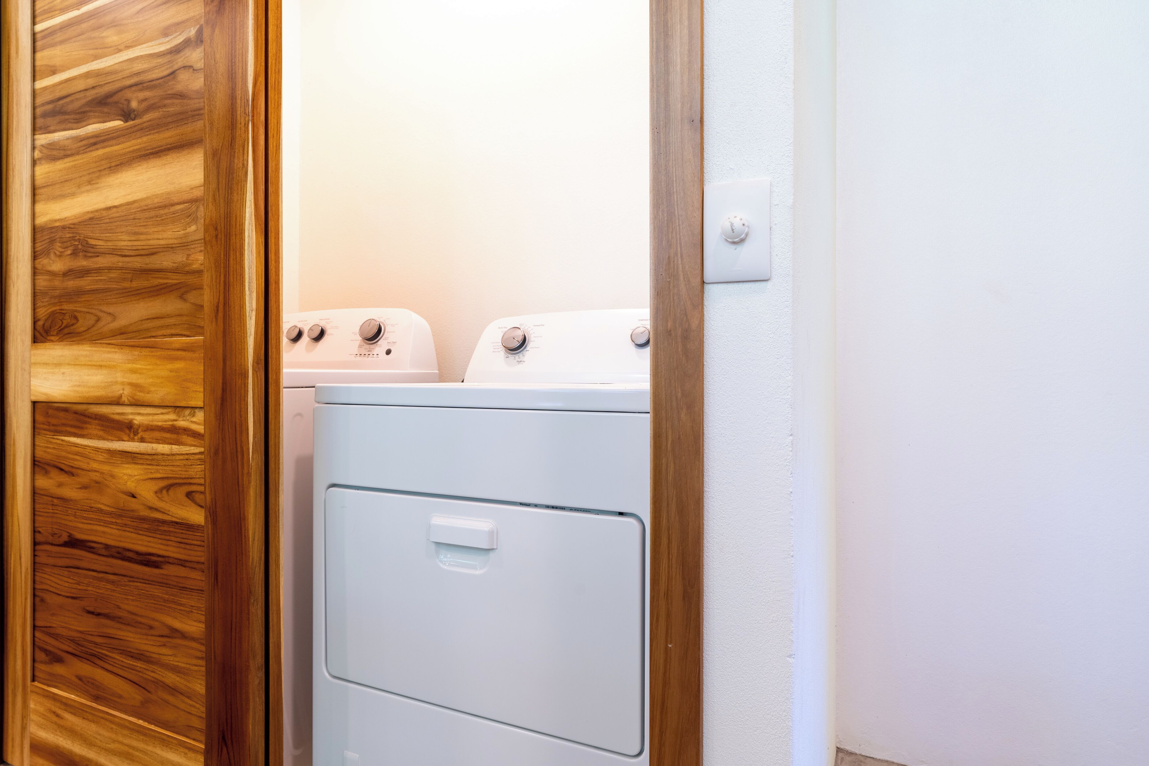 A laundry room with a wooden door and two white washing machines.