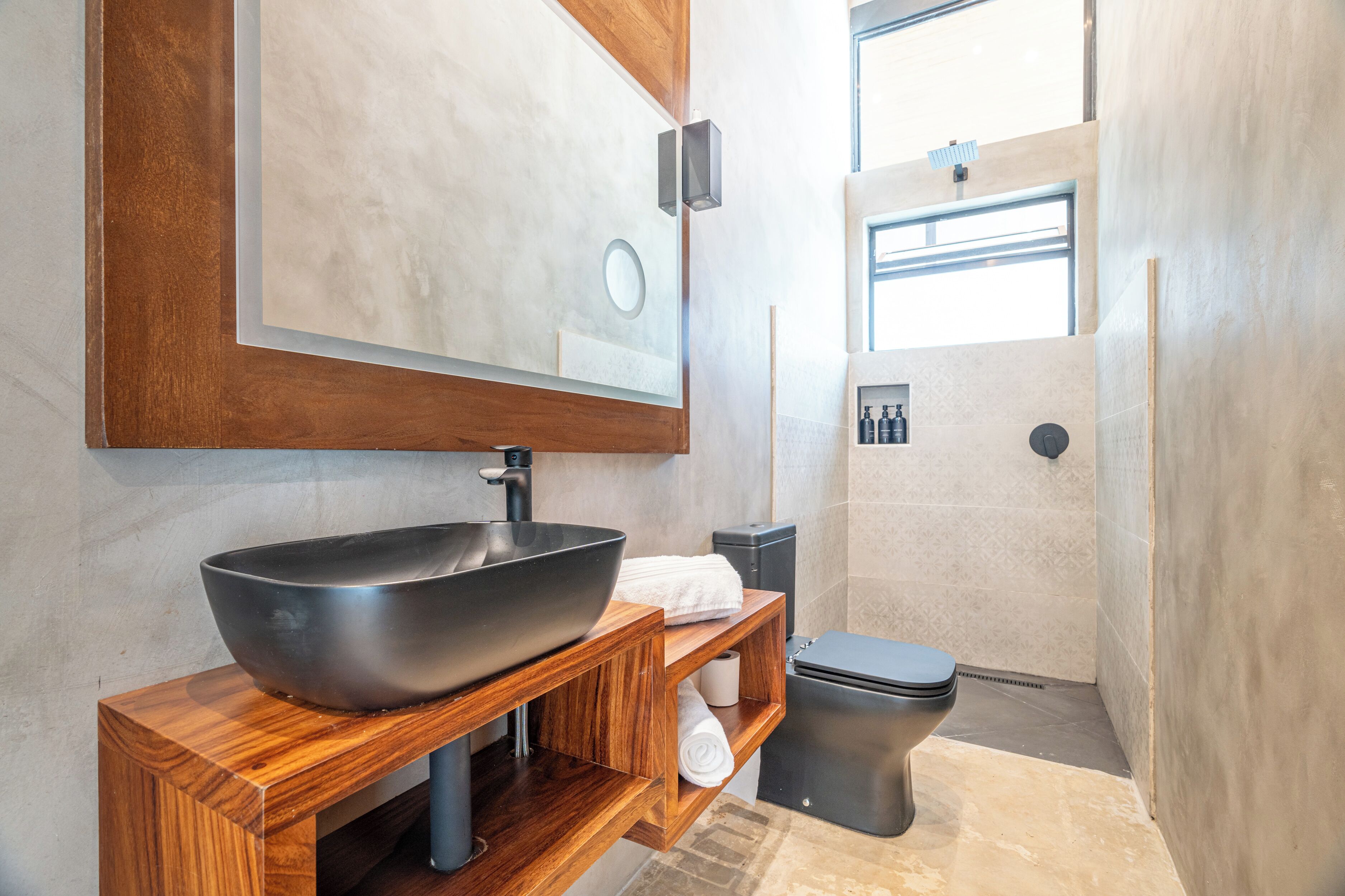 A modern bathroom with a large vessel sink, wooden vanity, and a toilet.