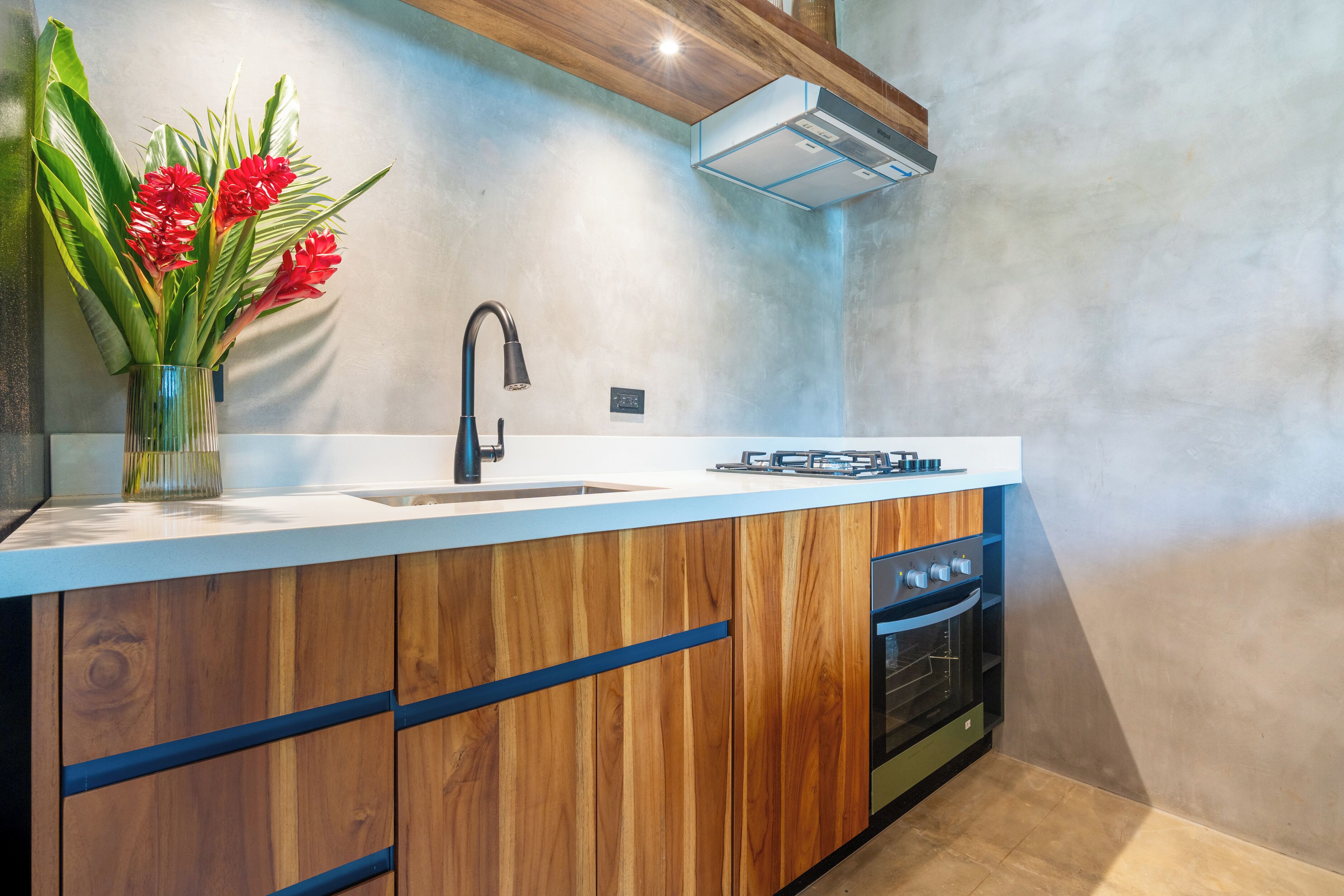 A modern kitchen with wooden cabinets, a stainless steel sink, and a built-in oven.