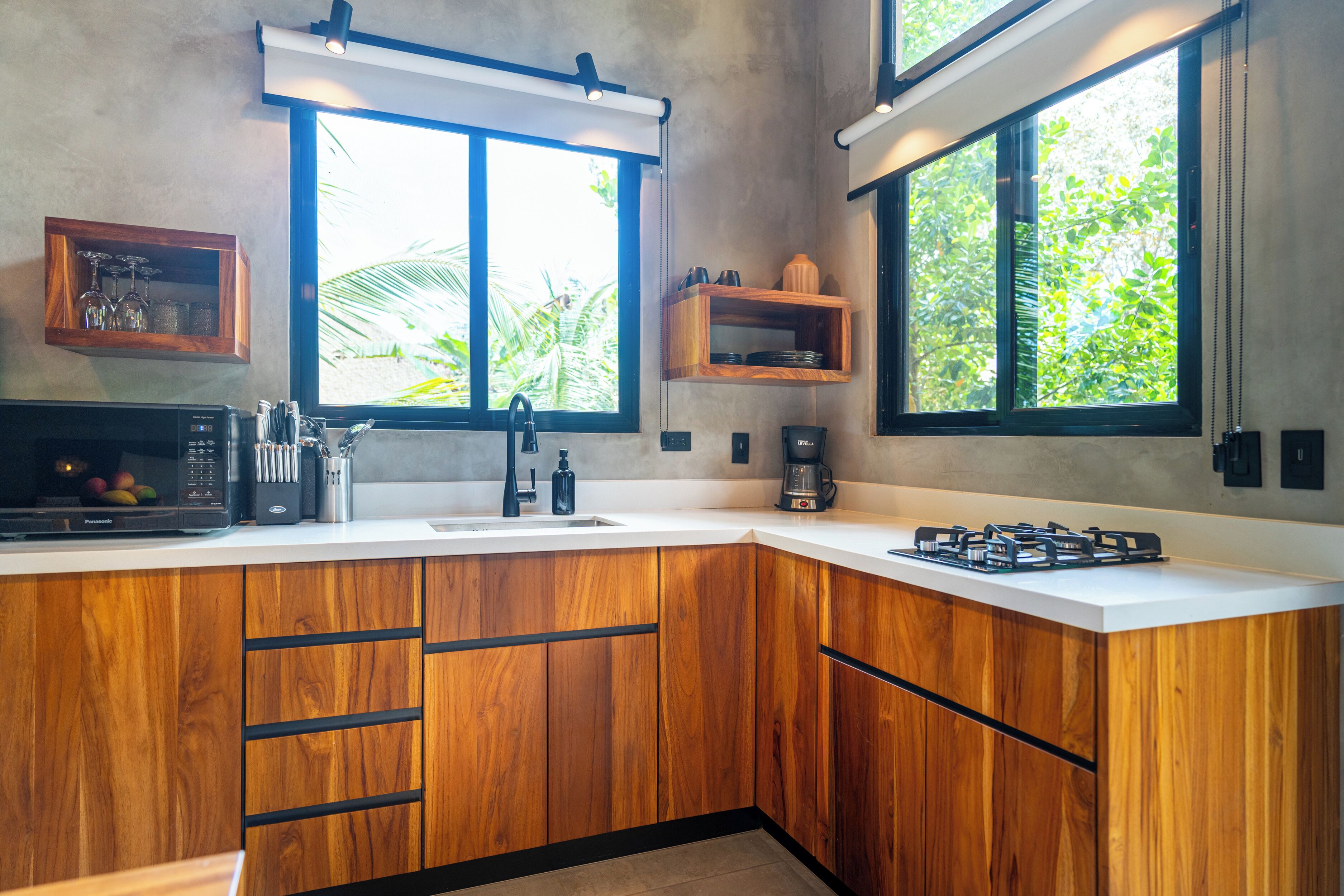 A modern kitchen with wooden cabinets, a gas stove, a microwave, and a coffee maker.