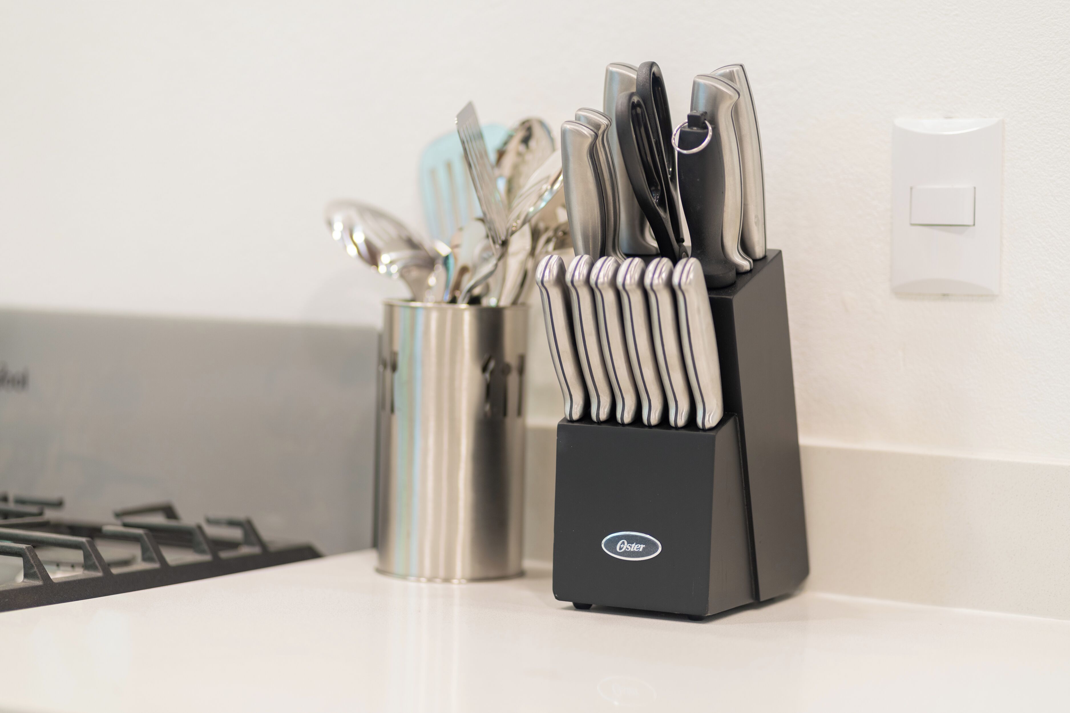 A kitchen counter with a knife block and a utensil holder.