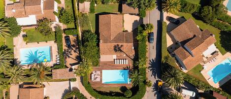 Vista aérea de una zona residencial con varias casas, una piscina y un jardín bien cuidado.