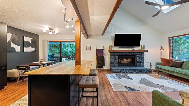 A modern living room with a wooden bar, a fireplace, a large TV, and a green sofa.
