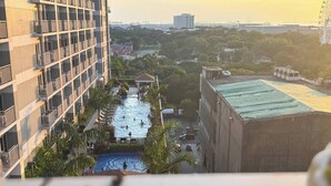 A high-rise building with a swimming pool and palm trees. - Levi & Moon's Home (Pasay)