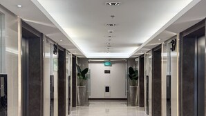 A modern hotel corridor with a polished marble floor, glass doors, and a clear exit sign. - Levi & Moon's Home (Pasay)