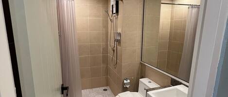 Un baño pequeño con inodoro, lavamanos y ducha.