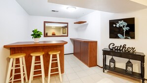A compact kitchen with a wooden bar and stools, a small cabinet, and a console table with lanterns. - Spokane Valley Escape (Spokane Valley)