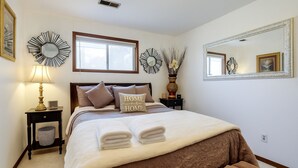 A neatly arranged bedroom with a bed, pillows, a bedside table with a lamp, a mirror, and decorative wall mirrors. - Spokane Valley Escape (Spokane Valley)