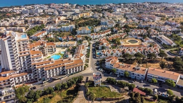 Un paysage urbain côtier avec un hôtel imposant, doté de plusieurs étages, d’une piscine et d’une cour intérieure.