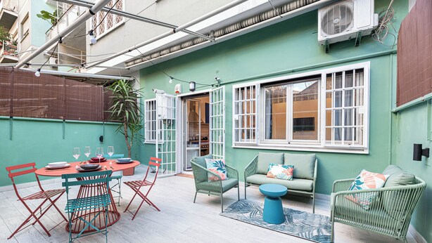 Une terrasse avec une table ronde et des chaises, un canapé et une petite table ronde.