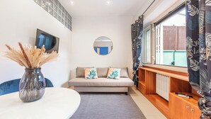 Un salon moderne avec un canapé, un miroir rond, un téléviseur et une fenêtre avec des rideaux.