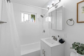 A modern bathroom with a bathtub, a sink with a mirror, and a window.