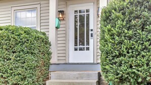 A house with a white front door, a window, and a small porch with steps.