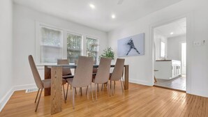 A dining area with a wooden floor, white walls, and a modern table with chairs.