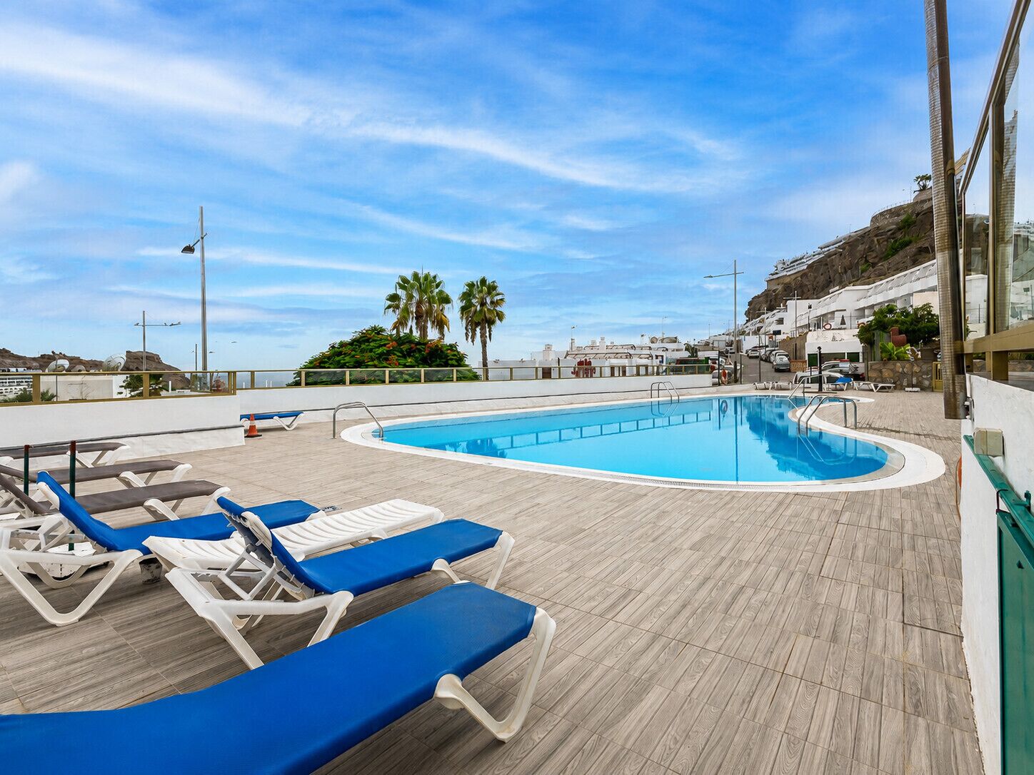 Zona de piscina con sillones de descanso y vista despejada al mar.