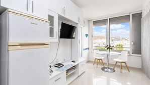 A modern kitchen with a built-in fridge, a flat-screen TV, and a dining area with a table and chairs.