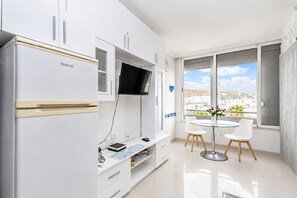 A modern kitchen with a built-in fridge, a flat-screen TV, and a dining area with a table and chairs.