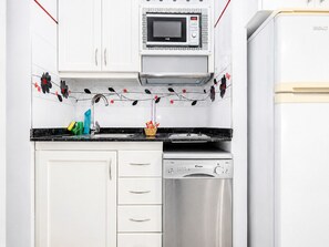 A kitchen with white cabinets, a microwave, a dishwasher, and a sink with a faucet. - Sun Port Ocean Views - Renovated & Pool 2 (Puerto Rico)