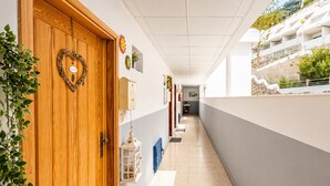 A corridor with a wooden door, a heart-shaped decoration, and a wall-mounted light fixture.