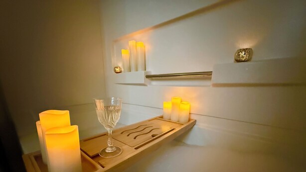 Un plateau avec des bougies, un verre et un objet décoratif, le tout posé sur une étagère fixée au mur.