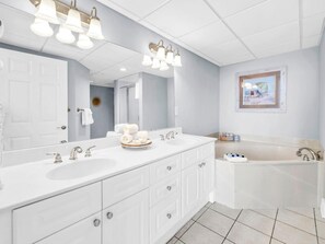 Un baño moderno con dos lavamanos, un espejo grande y una bañera.
