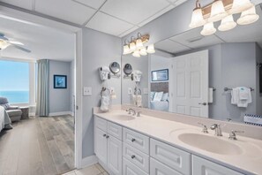 Un baño moderno con un tocador amplio, lavamanos dobles y un espejo grande.