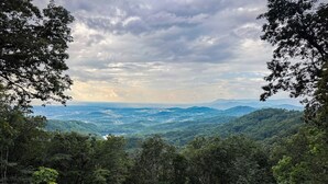 A panoramic view of a lush, green valley with dense forests and rolling hills. - Tranquil Escape: Hot Tub, Scenic Views, Family Fun (Ranger)