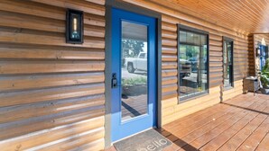 A wooden cabin with a blue door, large windows, and a wooden deck. - King Bed | Boho Charm | 2 minutes to Downtown (Eureka Springs)