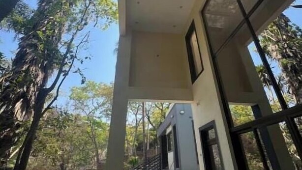 A modern building with large windows, a pool, and a staircase leading to the entrance. - Bamboo-view Breeze Suite (Glenlorne)