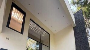 A modern building with large glass doors, a stone wall, and a tiled patio area. - Bamboo-view Breeze Suite (Glenlorne)