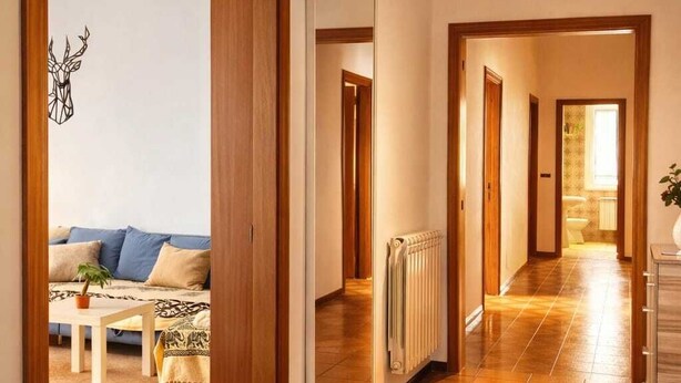 Ein geräumiger Flur mit Holztüren und Fliesenboden, der in einen Wohnbereich mit Sofa und kleinem Tisch führt.