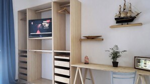 Ein Zimmer mit einem Holztisch, einem Fernseher, einem Schiffsmodell, einer Pflanze und einem Stuhl.