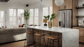 Une cuisine moderne dotée d’un grand îlot central, de tabourets de bar, de meubles en bois et d’un réfrigérateur.