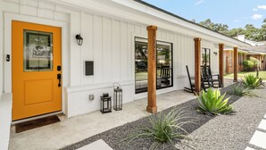 A white building with a yellow door, black lanterns, and a gravel pathway with plants. - Luxurious & Tranquil 3-bedroom House & Garden in Houston (Houston)