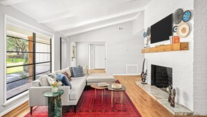 A spacious living room with a large window, a fireplace, and a modern sofa. - Luxurious & Tranquil 3-bedroom House & Garden in Houston (Houston)