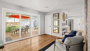 A spacious living room with a wooden floor, a grey sofa, and a black and white rug. - Luxurious & Tranquil 3-bedroom House & Garden in Houston (Houston)