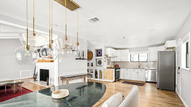 A modern kitchen with white cabinets, a central island, and hanging pendant lights. - Luxurious & Tranquil 3-bedroom House & Garden in Houston (Houston)