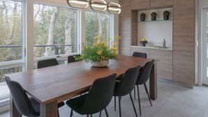 Een moderne eetruimte met een houten tafel, zwarte stoelen en een hanglamp.