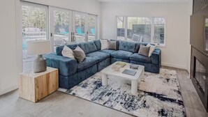 Een moderne woonkamer met een hoekbank, een salontafel en een open haard.