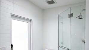Une salle de bain moderne avec une douche à parois de verre, des toilettes blanches et un lavabo avec un plan de travail.