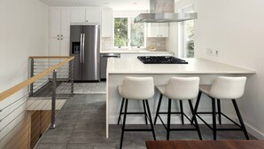 Een moderne keuken met een roestvrijstalen koelkast, een gasfornuis en een groot kookeiland met barstoelen.