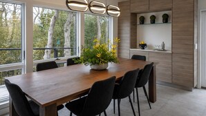 Un espace repas moderne avec une table en bois, des chaises noires et une plante en pot.