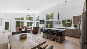 A modern kitchen with a large island, bar stools, and a dining table. - Summer Breeze at Goose Rocks Beach (Kennebunkport)